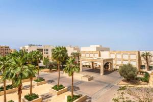 - une vue sur une ville avec des palmiers et des bâtiments dans l'établissement Hilton Dead Sea Resort & Spa, à Sowayma