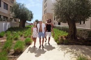 Un groupe de trois personnes marchant sur un trottoir dans l'établissement Hilton Dead Sea Resort & Spa, à Sowayma
