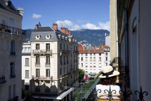 Una mujer parada en un balcón con vistas a una ciudad en Le Grand Hôtel Grenoble, BW Premier Collection by Best Western, en Grenoble