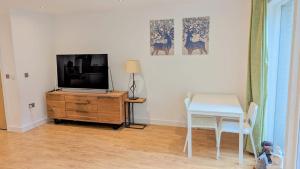 a living room with a tv and a desk and a table at 3 Bedroom house in Camberwell in London