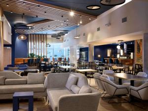 a lobby with couches and tables and a restaurant at Novotel Ieper Centrum in Ypres
