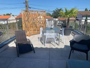 eine Terrasse mit einem Tisch, Stühlen und einem Zaun in der Unterkunft Maison terrasse proche centre ville et ile de Ré in La Rochelle