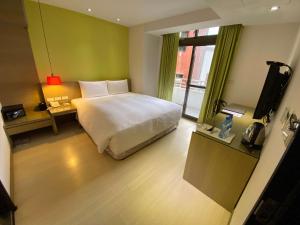 um quarto com uma cama e uma televisão em Ramada Encore By Wyndham Hualien em Hualien City