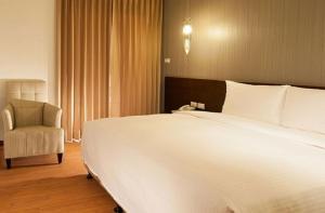 1 dormitorio con 1 cama blanca grande y 1 silla en Ramada Encore By Wyndham Hualien, en Hualien City