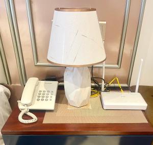 a lamp on a table next to a phone and a phone at Ocean breeze Hotel Studio Negombo by Shane in Negombo