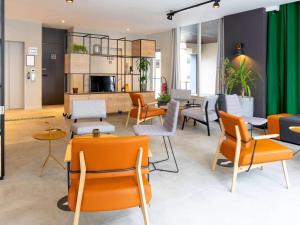 a waiting room with orange chairs and tables at Ibis Pau Centre in Pau