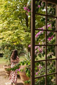 a woman sitting in a garden looking out a window at flowers at Exclusive Wine Resort - Villa Dianella in Vinci