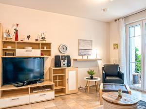 a living room with a large television and a chair at Achtern Diek Wohnung 06 in Boltenhagen
