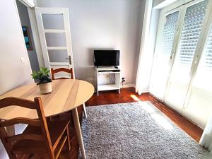 een kleine woonkamer met een tafel en een televisie bij Lisbon traditional T2 with balcony in Damaia, Lisbon in Amadora