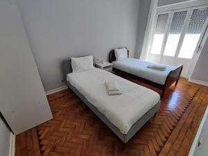 Duas camas num pequeno quarto com pisos em madeira em Lisbon traditional T2 with balcony in Damaia, Lisbon na Amadora
