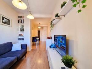 un salon avec un canapé bleu et une télévision à écran plat dans l'établissement Centric El Secreto del Pilar ComoTuCasa, à Saragosse