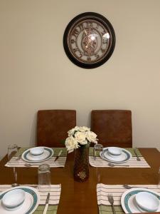stół z dwoma krzesłami i zegarem na ścianie w obiekcie Elegant Escapes 3 w Atenach