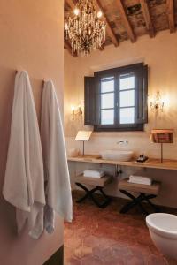 a bathroom with a sink and a toilet and a chandelier at Exclusive Wine Resort - Villa Dianella in Vinci