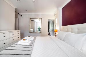Schlafzimmer mit einem großen weißen Bett und einem Spiegel in der Unterkunft Bright Spacious 2BR Apt, Chancery Lane in London