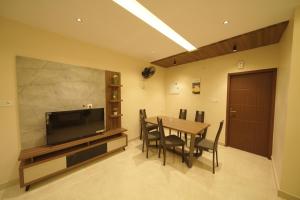 comedor con mesa y TV de pantalla plana en Ncomforts Luxurious Apartments, en Perintalmanna