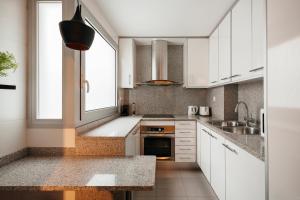 a kitchen with white cabinets and a sink and a window at TSA Sepulveda in Barcelona