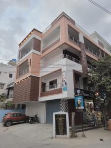 een roze gebouw met een auto ervoor geparkeerd bij New Premium Fully Furnished 2 BHK Flats Near Station in Tirupati