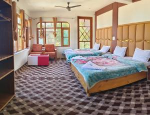 a bedroom with two beds and a chair at Hotel Gulsitara-Kunzer Gulmarg in Gulmarg