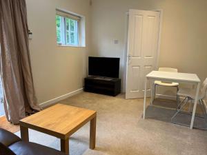a living room with a table and a television at The Cherwell Garden Annexe in Oxford