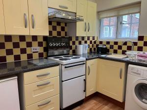 a kitchen with yellow cabinets and a stove top oven at The Cherwell Garden Annexe in Oxford