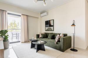 a living room with a green couch and a table at Radiant 2BR Apartment in Neo Psichiko by UPSTREET in Athens