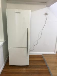 a white refrigerator in a room with a wall at A cozy place in Noble Park