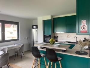a kitchen with green cabinets and a counter with chairs at Luna,central,self-check in,AC,WI-FI, washer,free parking in Zaprešić