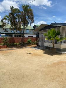 una casa con una valla y palmeras delante de ella en Klein-kronenburg Bakkershuisje, en Paramaribo