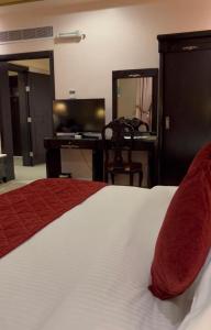 a bedroom with a bed and a desk and a television at Levant Hotel in Najran