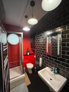 uma casa de banho com um lavatório, um WC e paredes vermelhas em Glasshouse yard studio's F1 em Londres