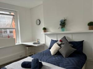 um quarto com uma cama azul e uma janela em Glasshouse yard studio's F1 em Londres