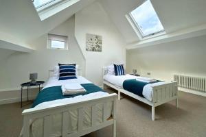 a bedroom with two beds and two skylights at Spacious 4 Bedroom Duplex with Free Private Parking - Central Location, Near Doncaster Racecourse - Sleeps 7 in Doncaster
