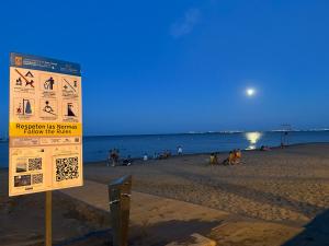 een bord op een strand met mensen op het strand bij Hotel Ribera in Santiago de la Ribera