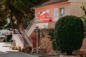 uma casa cor-de-rosa com uma escada ao lado. em Matilde Beach Resort em Vodice