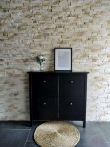 a black dresser in a room with a brick wall at Maison de vacances in Appenwihr