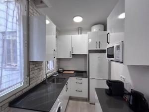 eine Küche mit weißen Schränken, einem Waschbecken und einem Fenster in der Unterkunft Nice flat in Gran Via CB-GRAC-18B in Madrid