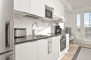 a white kitchen with a sink and a microwave at Kotimaailma - Kompakti kaunis yksiö kahdelle, Leppävaara in Helsinki