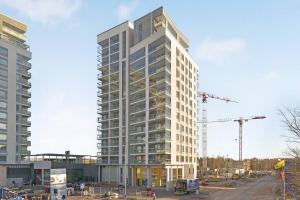 a tall white building with construction cranes at Kotimaailma - Kompakti kaunis yksiö kahdelle, Leppävaara in Helsinki