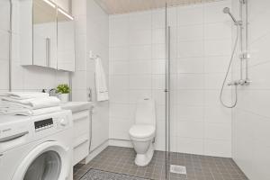 a white bathroom with a toilet and a shower at Kotimaailma - Kompakti kaunis yksiö kahdelle, Leppävaara in Helsinki