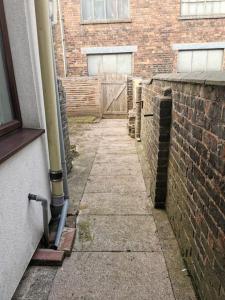 a brick wall next to a sidewalk next to a building at 2 bedroom house, Tunstall, Stoke-on-Trent. in Stoke on Trent