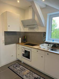 une cuisine avec des armoires blanches, un évier et une fenêtre dans l'établissement Übernachtung by Tag, à Staufenberg