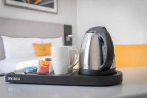 uma chaleira e uma chávena numa mesa num quarto de hotel em Maldron Hotel Merrion Road em Dublin