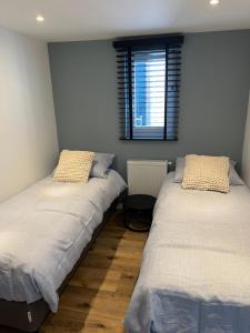 two twin beds in a room with a window at Luxe woning ‘BARNS’ Castricum aan Zee + airco + parkeren in Castricum