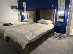 ein Schlafzimmer mit einem großen Bett mit blauer Wand in der Unterkunft Amazing 2 Bedrooms House in Bridgend