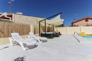 a patio with white chairs and a swimming pool at Chalet para 12 personas con piscina en Illescas Toledo in El Viso de San Juan