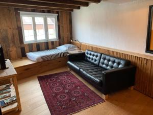 a living room with a black leather couch and a bed at Hausele in Sulzbach an der Murr