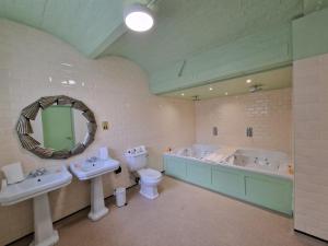 a bathroom with two sinks and a tub and a toilet at RainHill Hall Hotel in Rainhull +94 photos