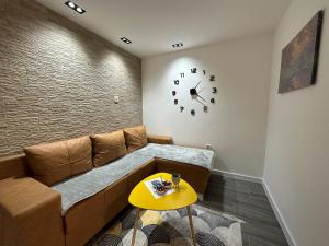 een woonkamer met een bank en een klok aan de muur bij Vucinic Studio Apartment in Cetinje
