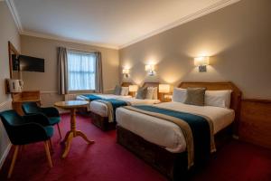 a hotel room with two beds and a chair at Harcourt Hotel in Dublin