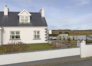 une maison blanche avec une clôture blanche dans l'établissement Matthews Traditional Holiday Cottage by Trident Holiday Homes, à Doonbeg